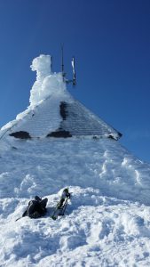 The summit building with skis and pack